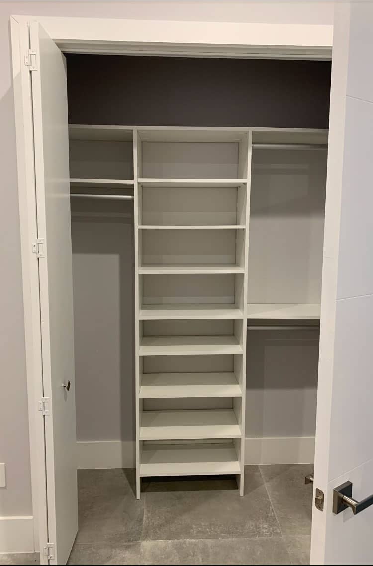 White reach-in closet behind open bifold doors, with a center shelf tower and double-hang rods on both sides