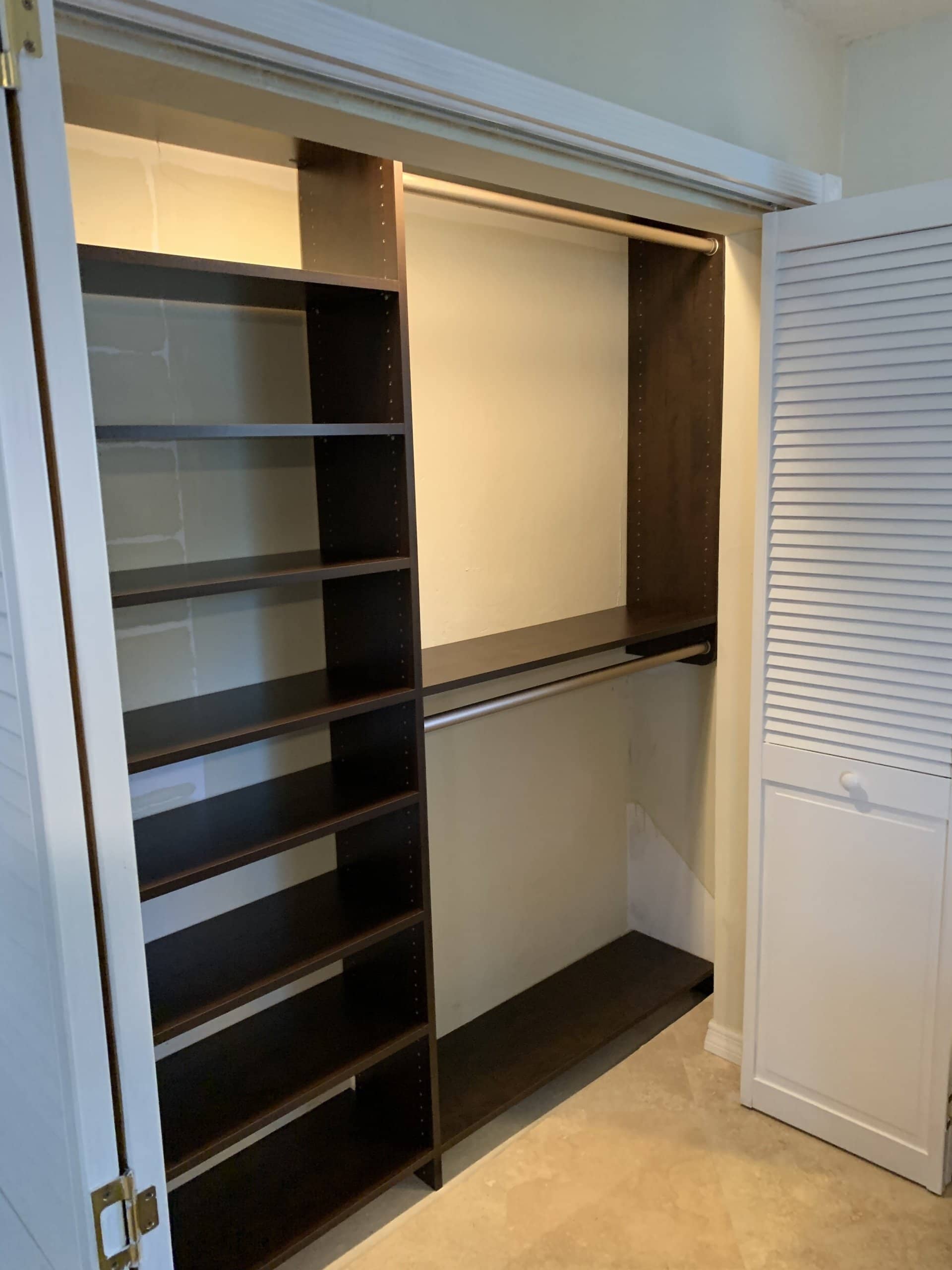 Chocolate Pear reach-in closet with a tall adjustable shelf tower beside double-hang rods, next to a louvered bifold door