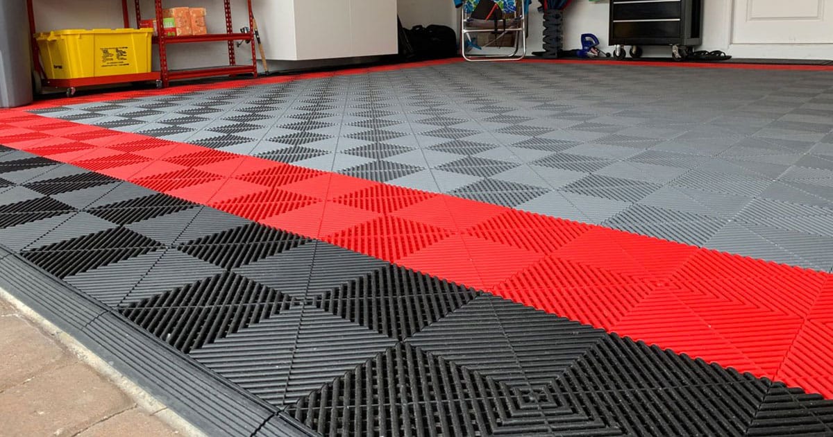 Red, black and gray Swisstrax floor tiles laid at the edge of a garage door opening