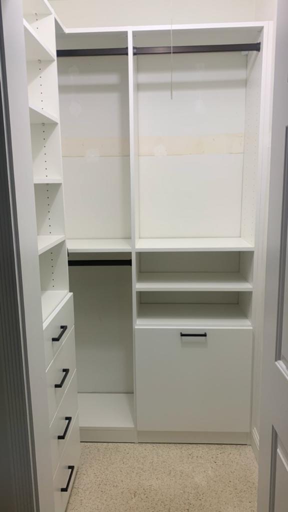White custom closet with panels that rest on a base at the floor, adjustable shelves, double-hang rods and a drawer stack with matte black pulls