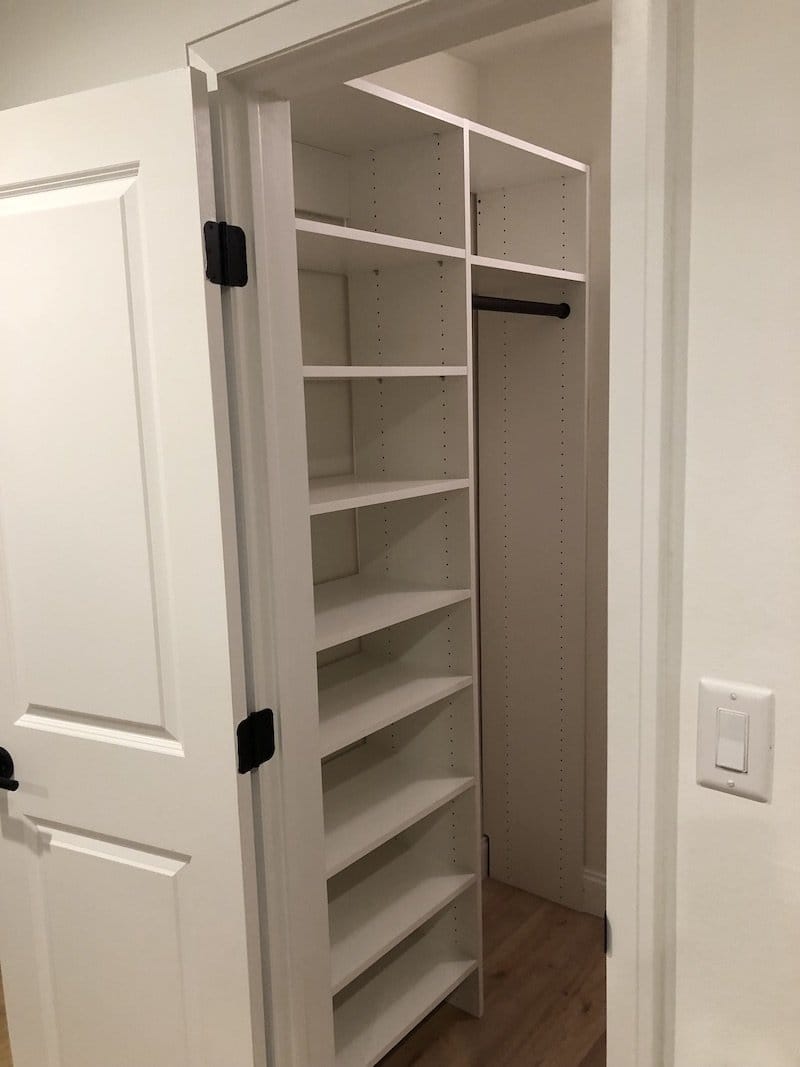 After: the finished closet with a white custom shelf tower, an upper shelf and a hanging rod