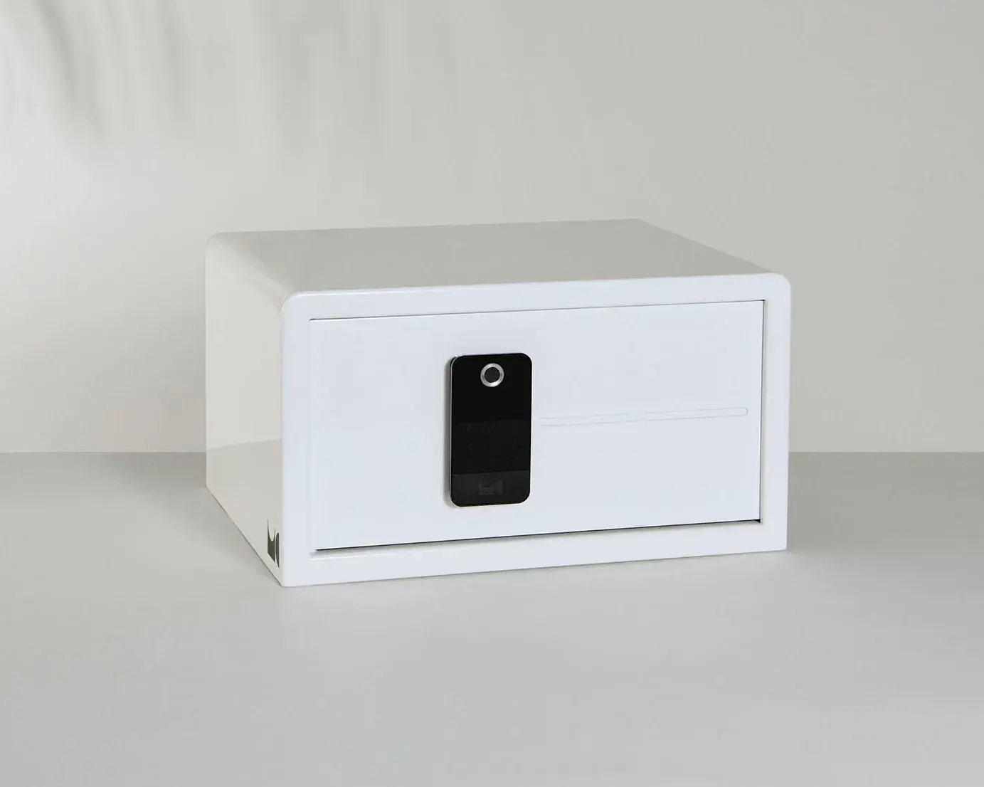 A white safe with a remote control is sitting on a table.