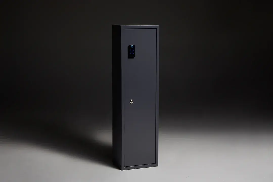 A black safe is sitting on a gray surface in a dark room.