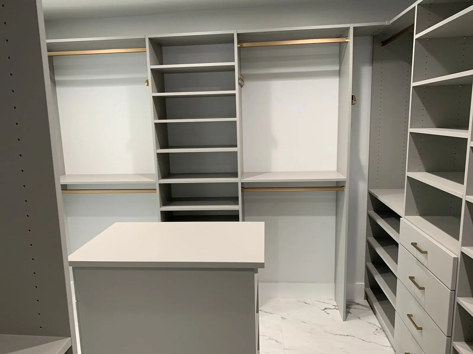 A walk in closet with lots of shelves and drawers.