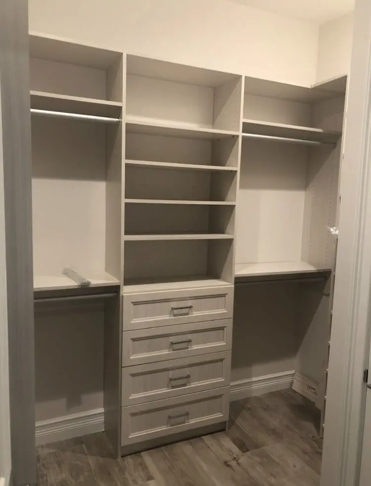 A walk in closet with lots of shelves and drawers.